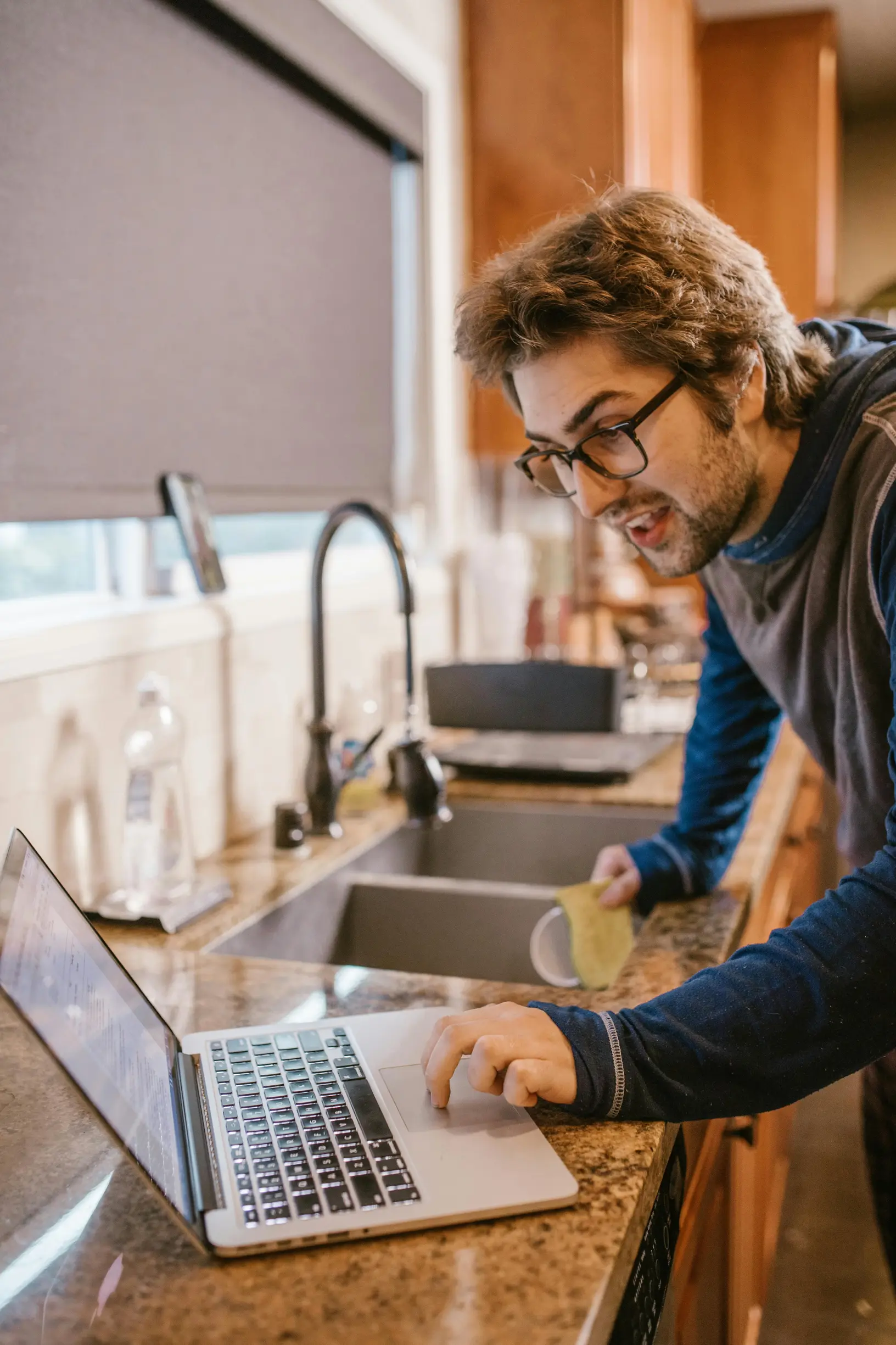 Adult man using laptop in kitchen for online learning, showcasing modern remote education concept.