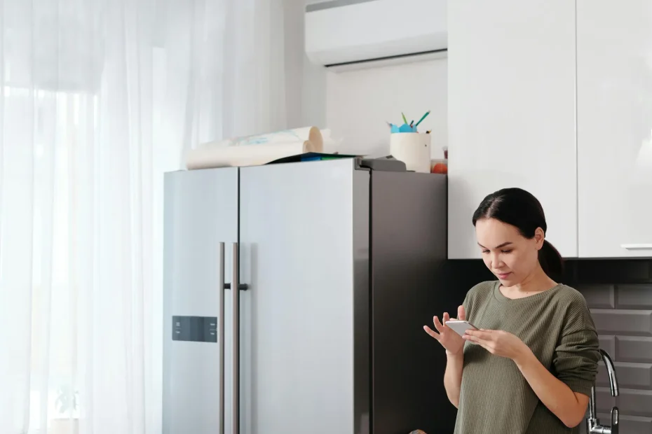 Adult woman using smartphone in a contemporary kitchen setting.