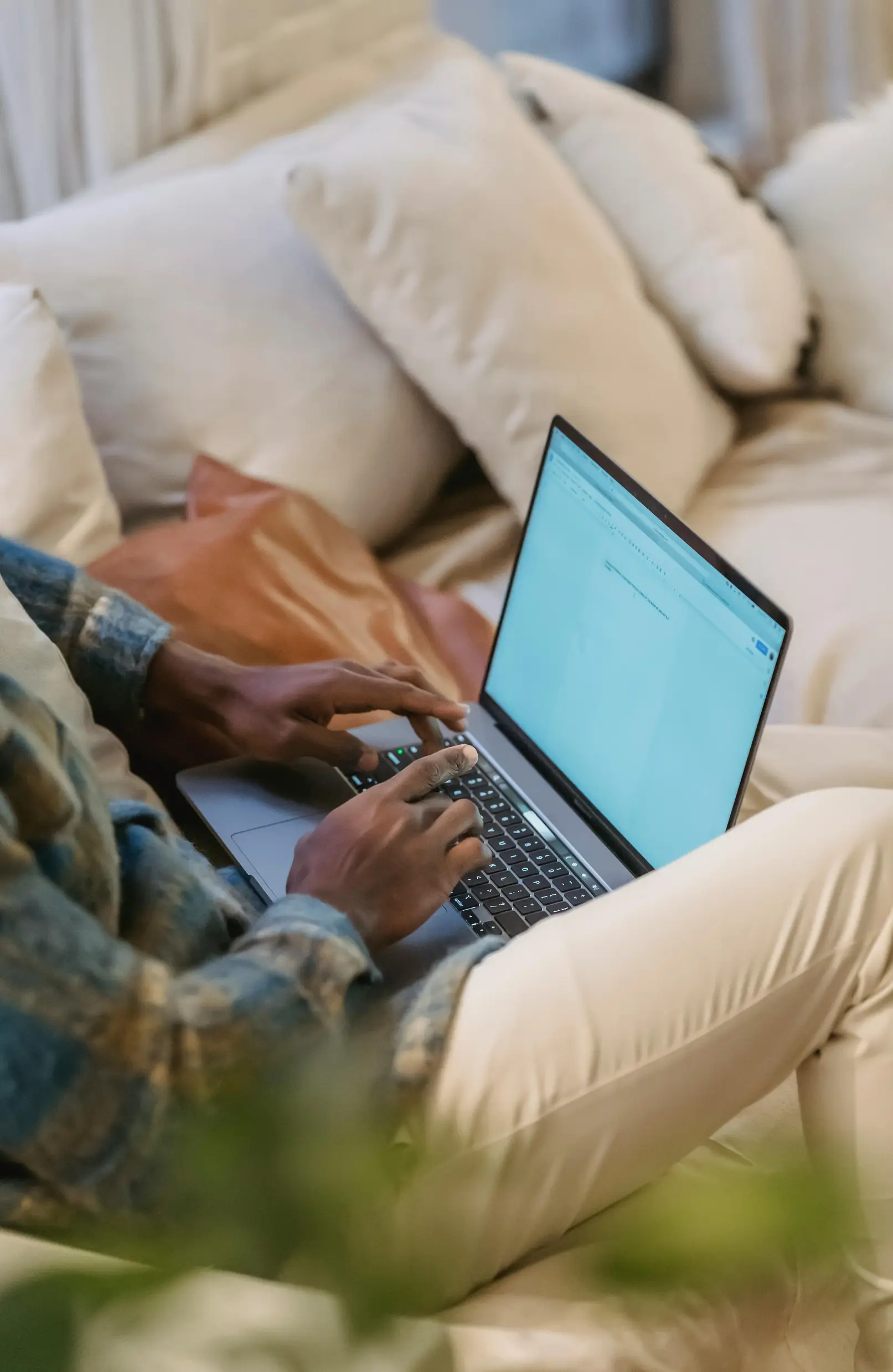 Adult working on laptop in cozy home setting, showcasing remote work lifestyle.