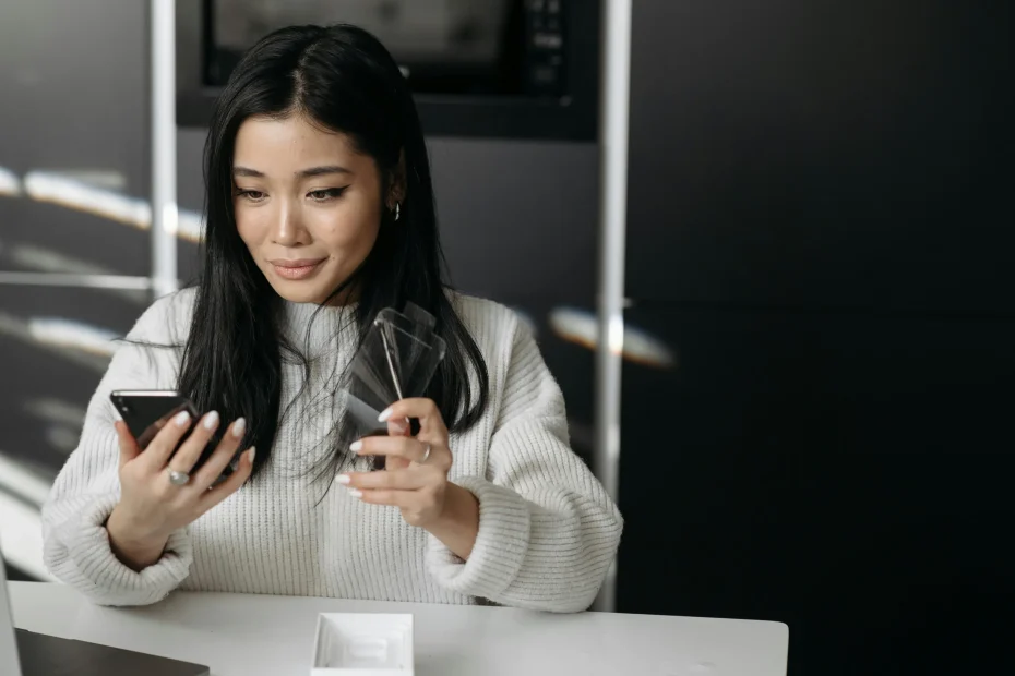 Woman unpacking and setting up a new smartphone device indoors.
