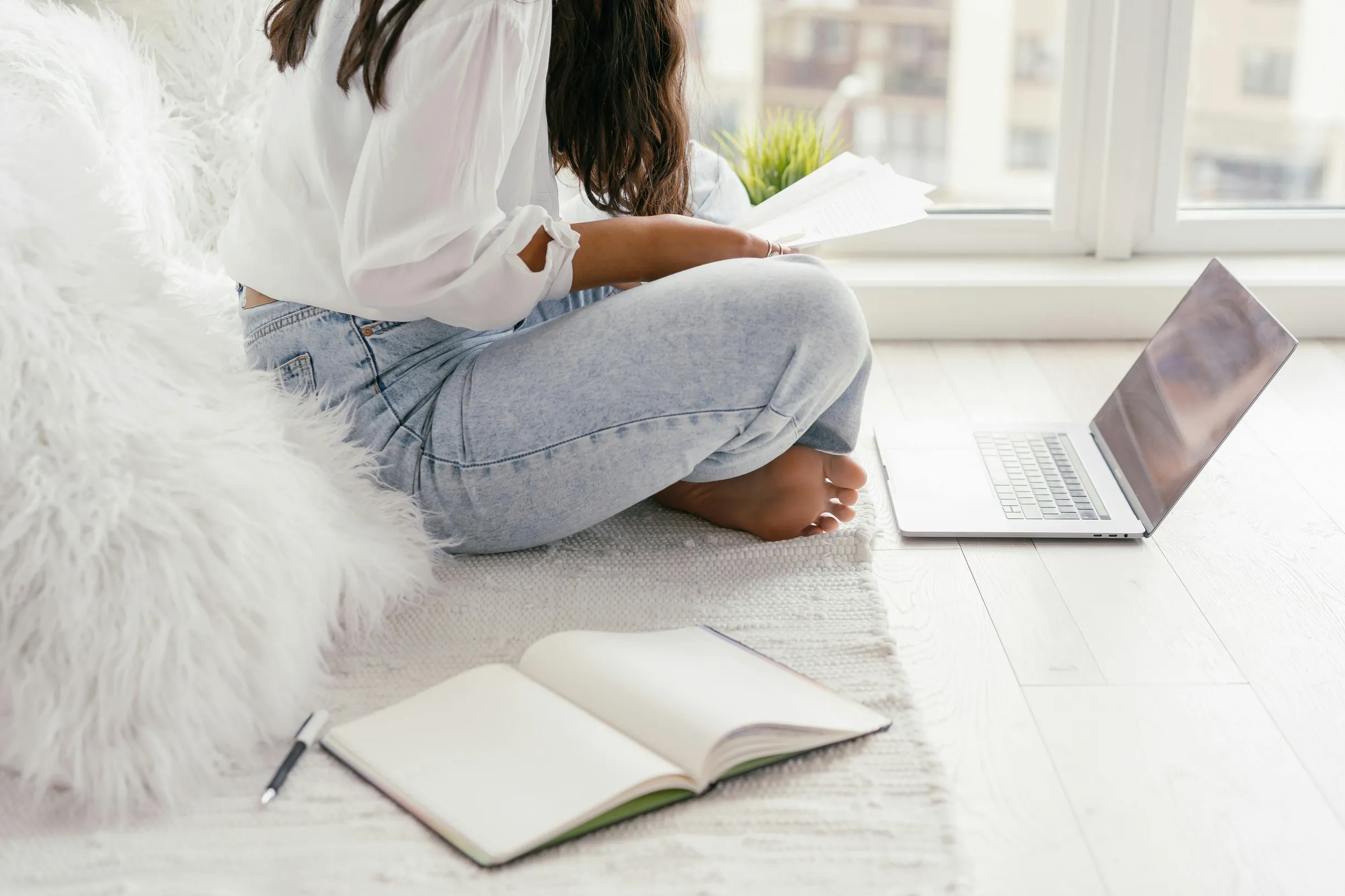 Young adult studying at home using a laptop and notebook, creating a cozy learning environment.
