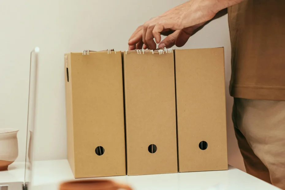 A person organizing files at a minimalist home office desk with a cup of coffee.