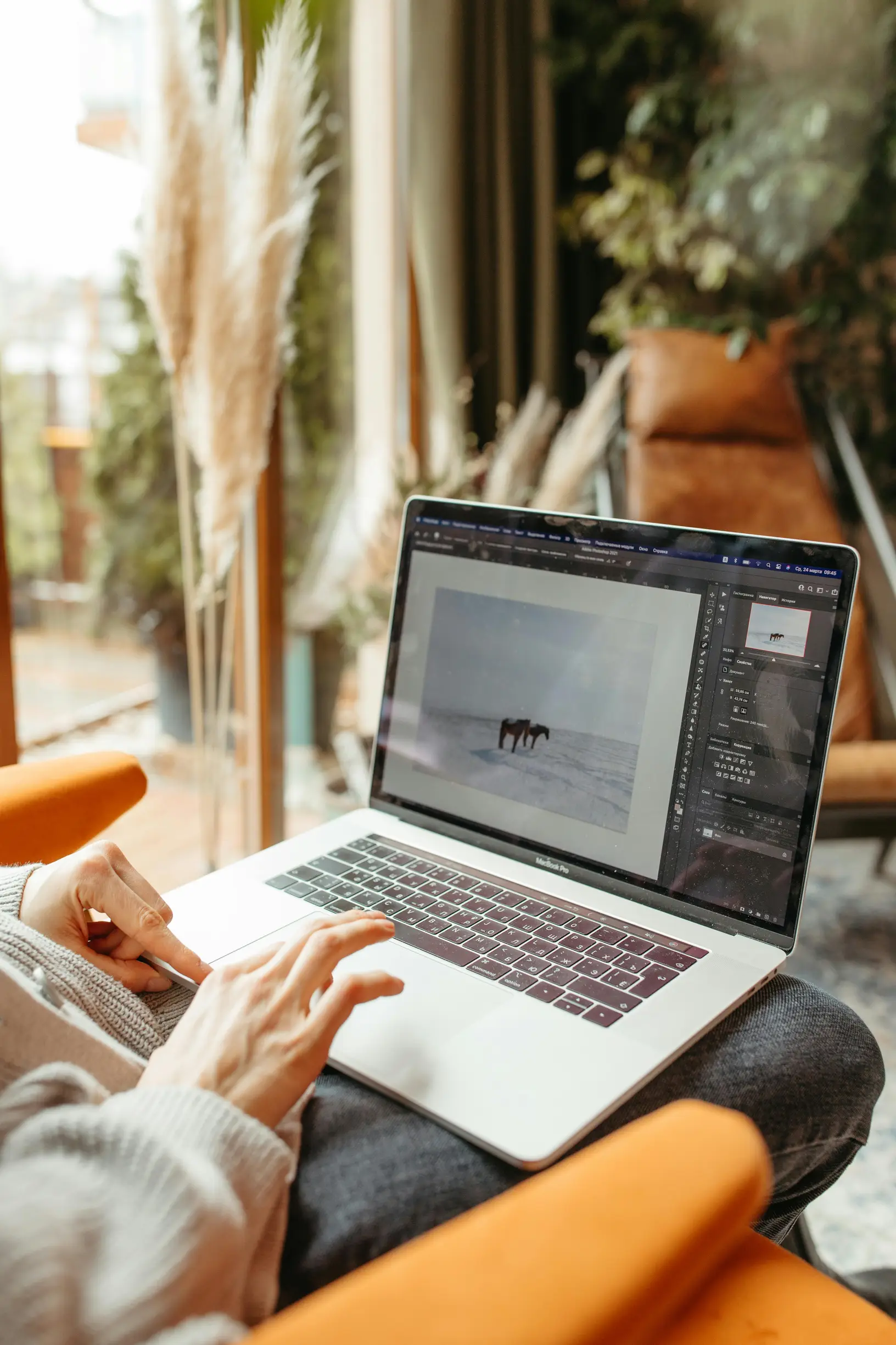 A person using a laptop for photo editing indoors with natural light.