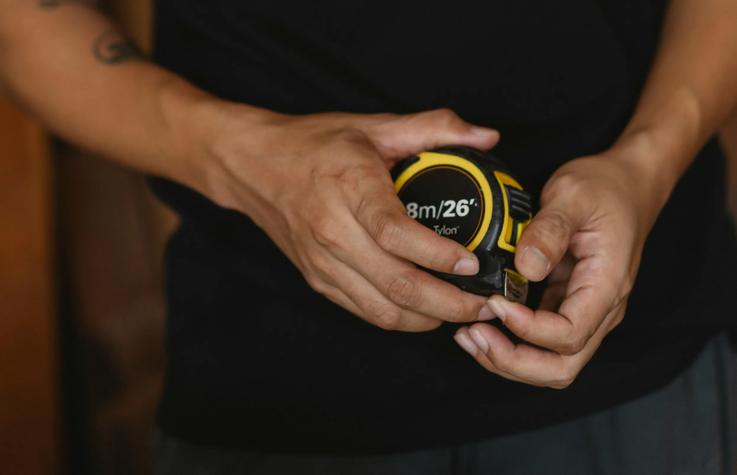 Detailed photo of a person holding a tape measure, emphasizing craftsmanship.
